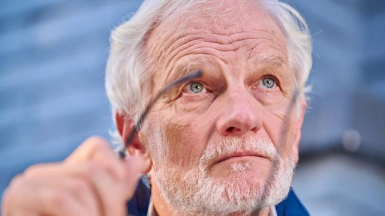 Elderly man holding glasses