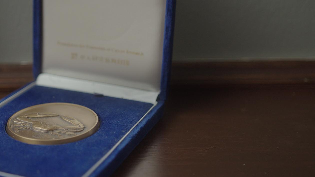 Medal with a crab engraved inside a blue box.